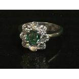 An 18ct white gold diamond and emerald cluster ring