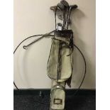 A metal hoop and a golf bag with hickory shafted drivers and Walter Glover irons