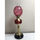 A Victorian cranberry glass oil lamp on gilt brass column