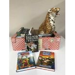 A box of assorted books and a large figure of a leopard