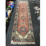 A fringed Turkish woolen runner on red ground