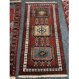 A geometric designed rug on red ground 187 cm x 87 cm