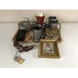 A tray of pewter tankards, trivets, hanging scales, bakelite cased weight,