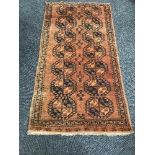 A Persian fringed woollen rug on rust ground