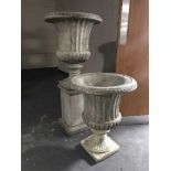 A pair of classical garden urns on stands (one with plinth)