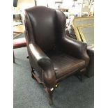 A Georgian style brown leather wingback armchair