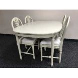 A cream and gilt dining table and four chairs