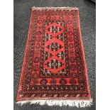 A Persian fringed woollen rug on red ground