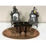 An oval copper serving tray with six goblets and a pair of ornate metal photo frames