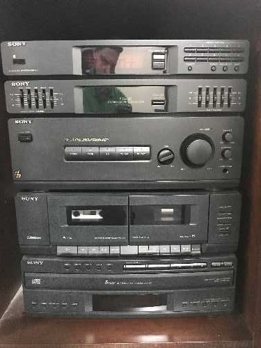 A mahogany audio cabinet containing a Sony hi/fi system with speakers and speaker stands