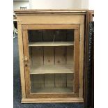 An antique striped pine glazed door wall cabinet