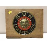 A Sun Londers insurance plaque mounted on a pine board