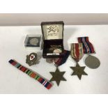 A trio of WWII medals with ribbons and military badges