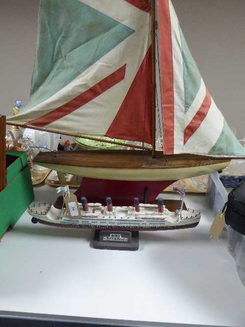 A large wooden pond yacht on stand and a model of the RMS Titanic