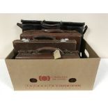 A box containing three small vintage leather luggage cases,