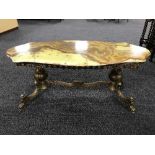 A shaped onyx topped coffee table on a brass base