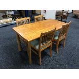 A rectangular kitchen table together with a set of four pine rail back chairs