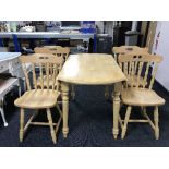 A circular pine drop-leaf kitchen table together with four chairs