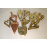 Ten 19th century brass and copper trivets of heart form, some pierced,