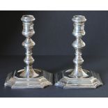 Pair of cast silver table candlesticks of early Georgian style with knopped stems on incurved