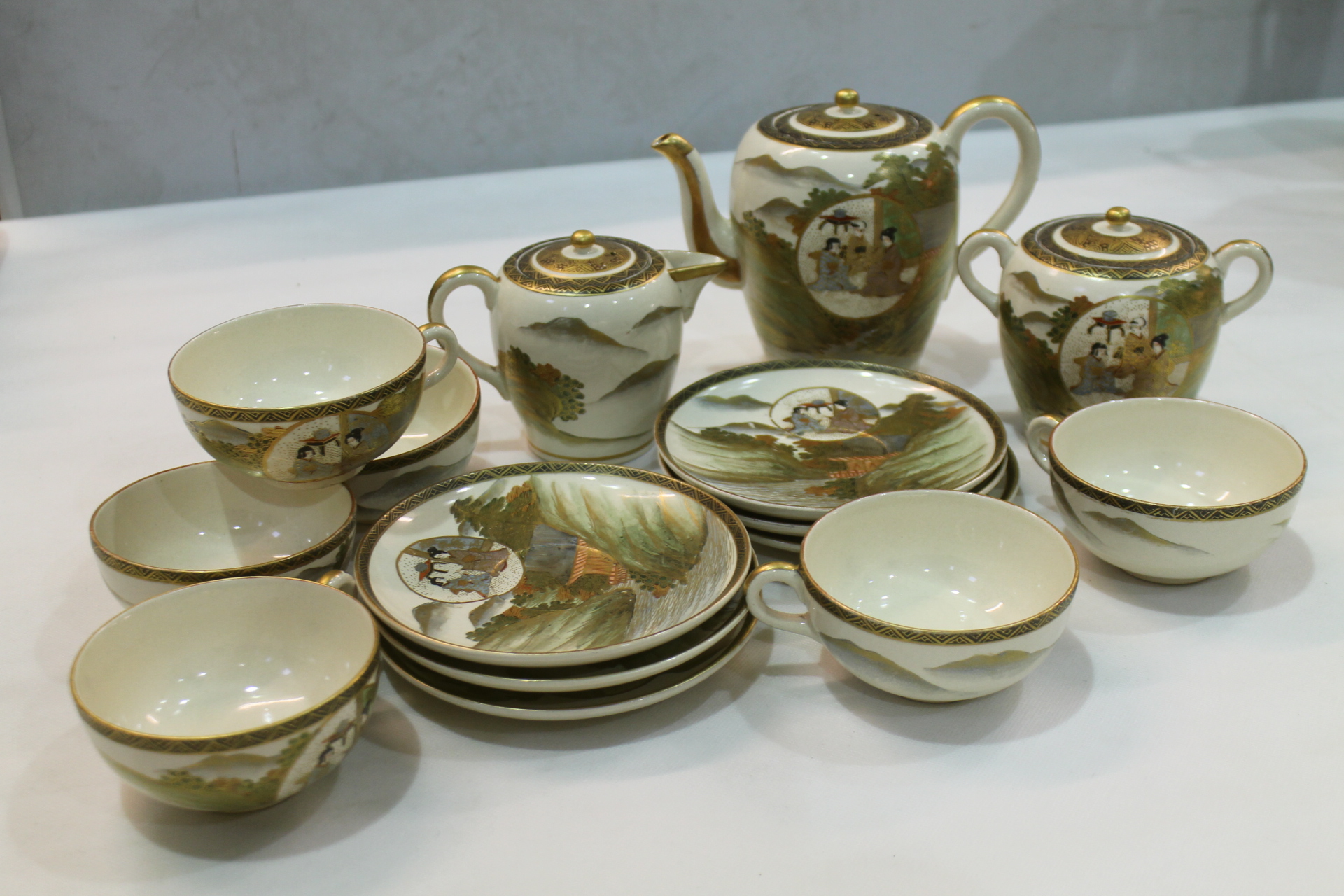 Japanese Satsuma tea set decorated with circular panels depicting teachings within rural landscape