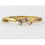 Victorian gold hinged bangle with three old cut brilliants flanked by angled openwork and engraved