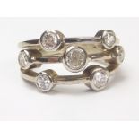 Dress ring with three bands of collet set diamond brilliants, seven in all, 9ct white gold,