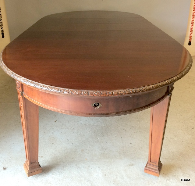 Warring and Gillows mahogany extending dining table on tapered legs with brass casters, carved