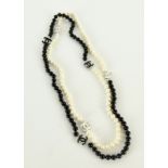 a long string of cream and black cultured pearls with Chanel style markers