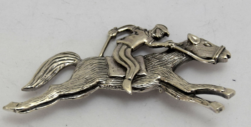 a silver horse and jockey brooch