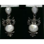 a pair of silver and moonstone earrings in the form of owls