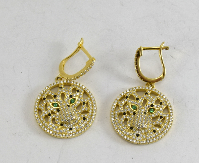 a pair of silver gilt earrings in the form of tigers with emerald eyes