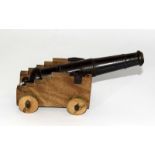 An impressive desk top cannon with an iron barrel mounted on a wooden carriage. Barrel is 18.5cms