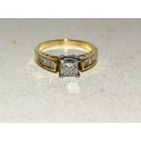 14ct yellow gold diamond ring with princess cut central stone and baguette cut diamond shoulders.
