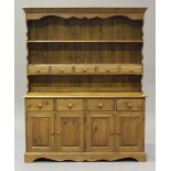 A modern pine dresser, the shelf back fitted with five drawers, the base fitted with drawers and