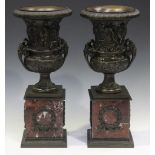 A pair of modern bronze decorative urns cast in relief with bands of classical figures, raised on