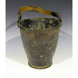 A 19th century leather sand bucket with strap handle and metal rim, bearing the remnants of a