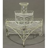 A late 20th century white painted demi-lune three-tier plant stand, raised on scrollwork legs,