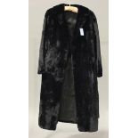 A mid-20th century black fur three-quarter length coat with black patterned lining, length 118cm.