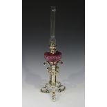 A late 19th century French plated brass table oil lamp with a facet cut cranberry glass reservoir,