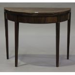 A George III mahogany demi-lune fold-over card table, the hinged top above a line inlaid frieze,