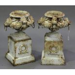 A pair of 20th century white painted cast iron garden urns, each low-bellied body decorated with