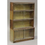 A mid-20th century Minty four-section oak bookcase with glass sliding doors, on a plinth base,