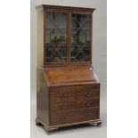 A George III mahogany bureau bookcase, the moulded pediment above a pair of astragal glazed doors,