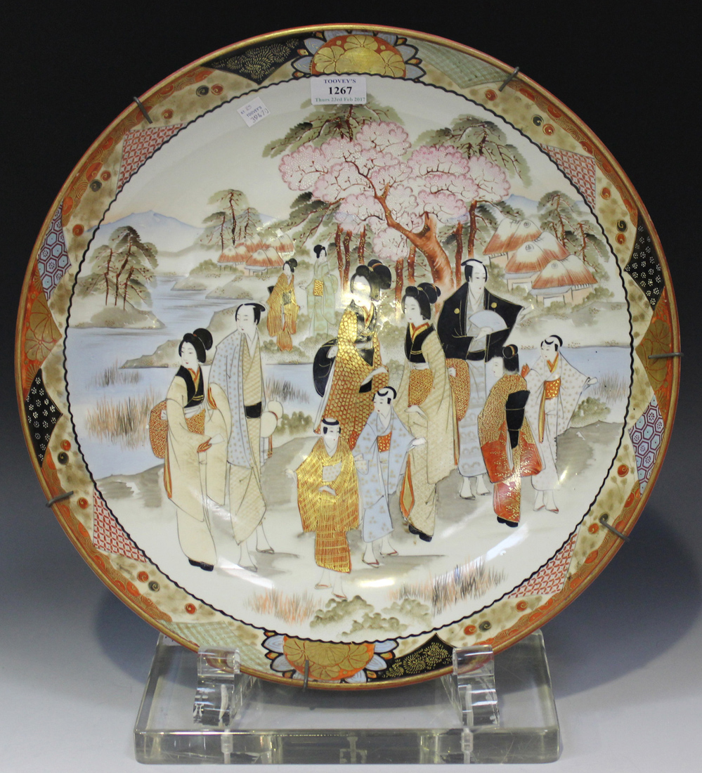 A Japanese Kutani porcelain charger, Meiji period, painted and gilt with figures in a lakeside