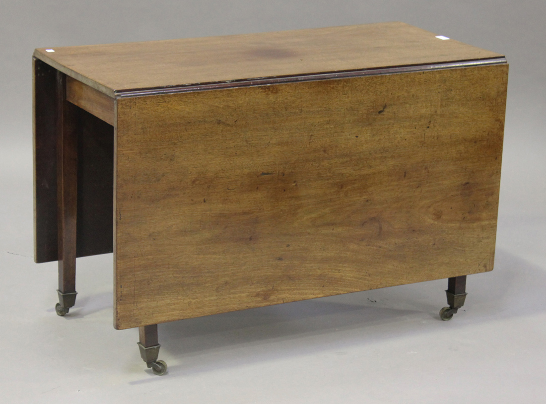 A George III mahogany drop-flap dining table, raised on square tapering legs with brass caps and