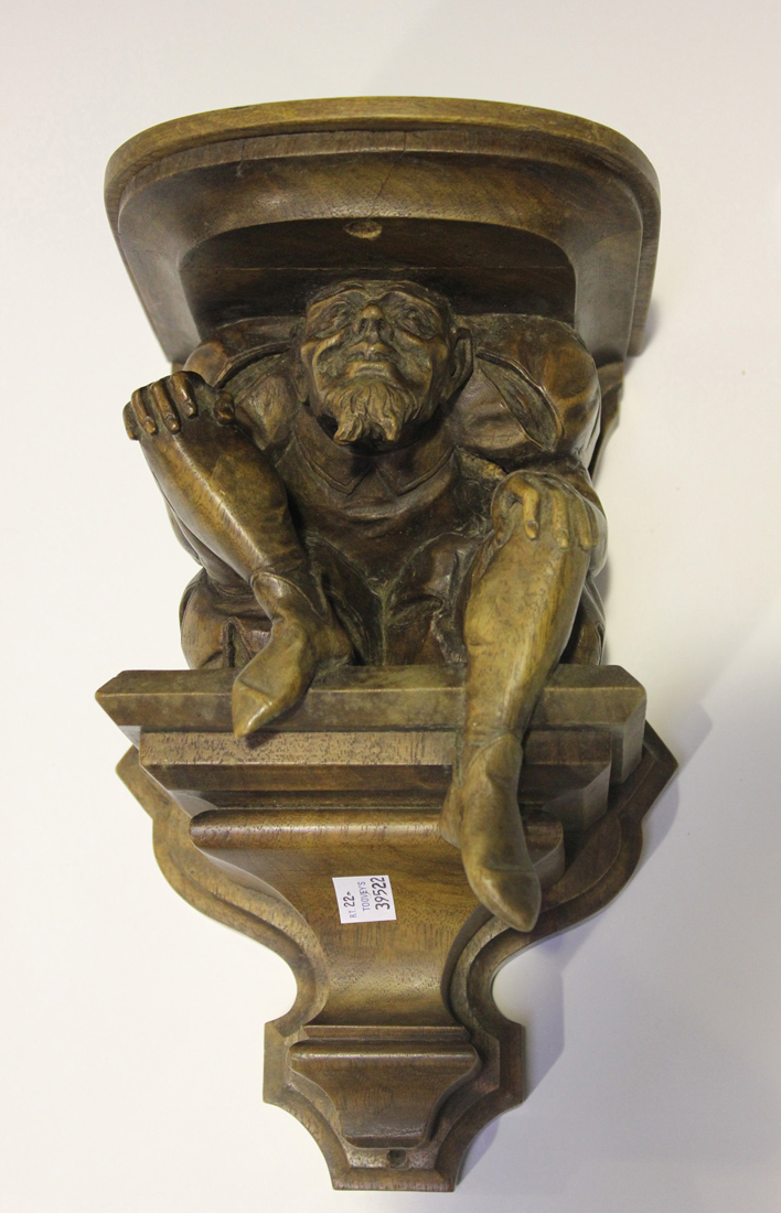 A late 19th century Continental carved walnut wall bracket, the moulded top supported by a seated