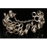 A silver wide wirework bracelet of abstract scrolling loop design with a hook shaped clasp, London