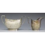 A late Victorian silver milk jug and sugar bowl, each of half reeded oval form, London 1894 by