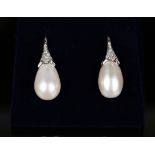 A pair of white gold, cultured pearl and diamond earrings, each oval pearl with a diamond set